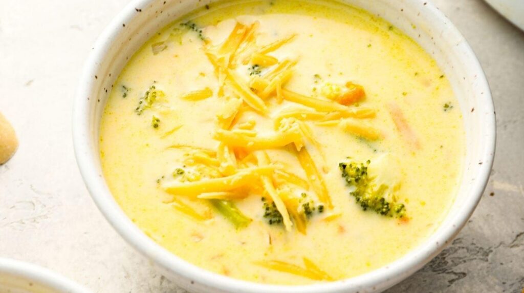 Ultra close-up macro of bubbling golden Panera style broccoli cheddar soup with tender green florets and melted cheese
