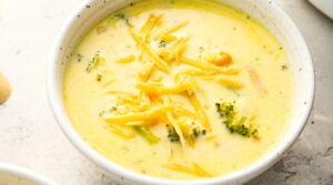 Ultra close-up macro of bubbling golden Panera style broccoli cheddar soup with tender green florets and melted cheese